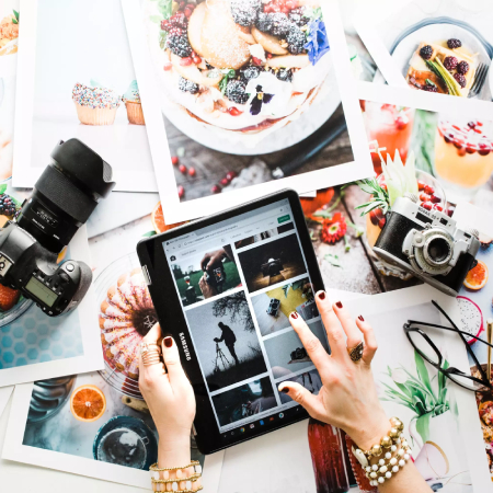 Image of A Woman Swiping Different Types of Images In Her Tablet Which Was Placed On The Table Full of Photographies.