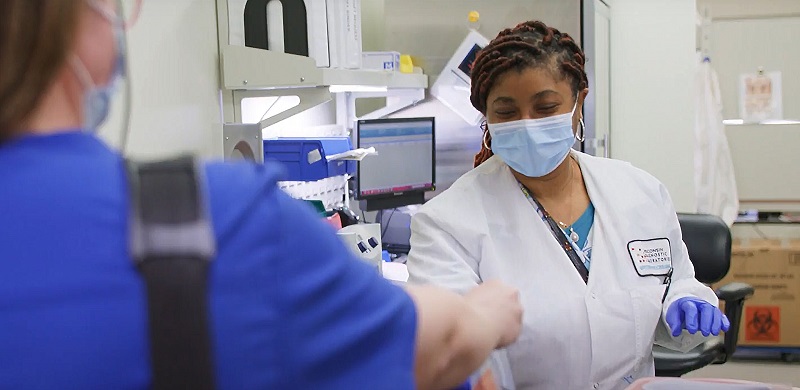 A Lab technician receiving test sample from one lady